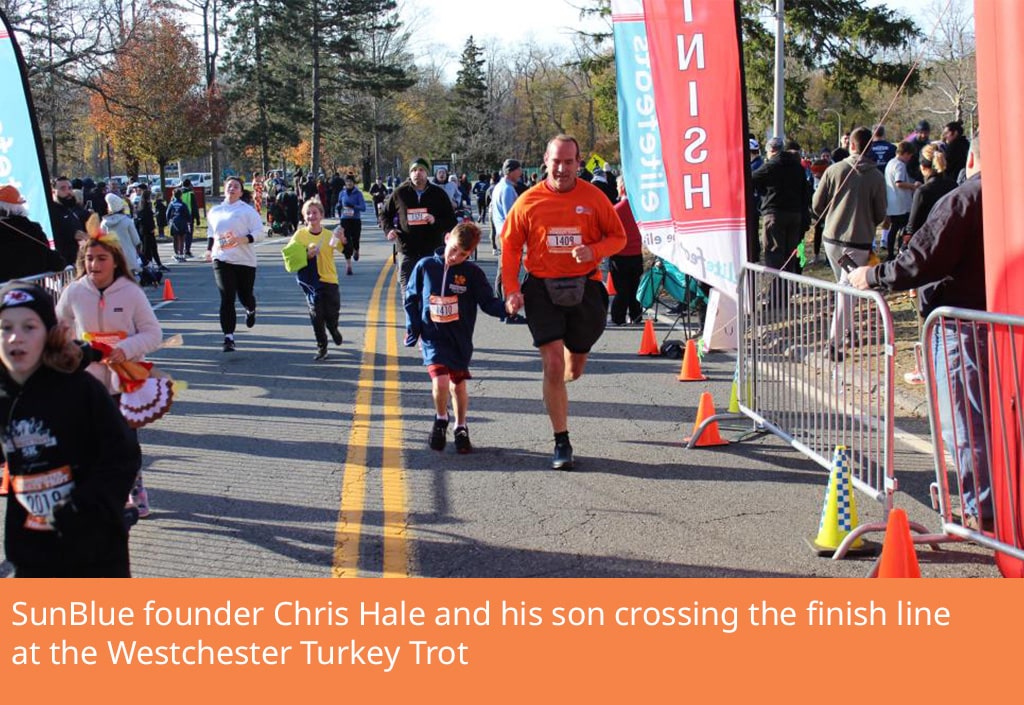 Man crossing turkey trot finish line with son